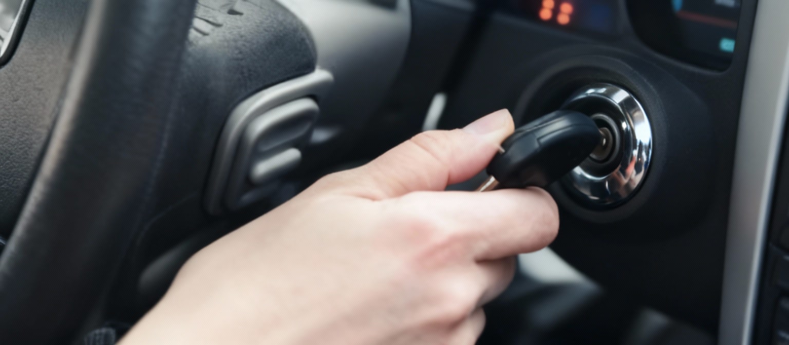 Mano girando la llave en el contacto de un coche que no arranca, mostrando el momento en que el conductor intenta ponerlo en marcha