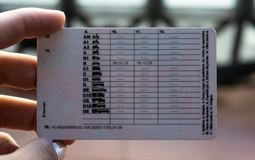 Imagen de un permiso de conducir europeo sostenido con la mano donde se observan claramente los códigos del carnet de conducir y su apartado 12, mostrando fechas y categorías