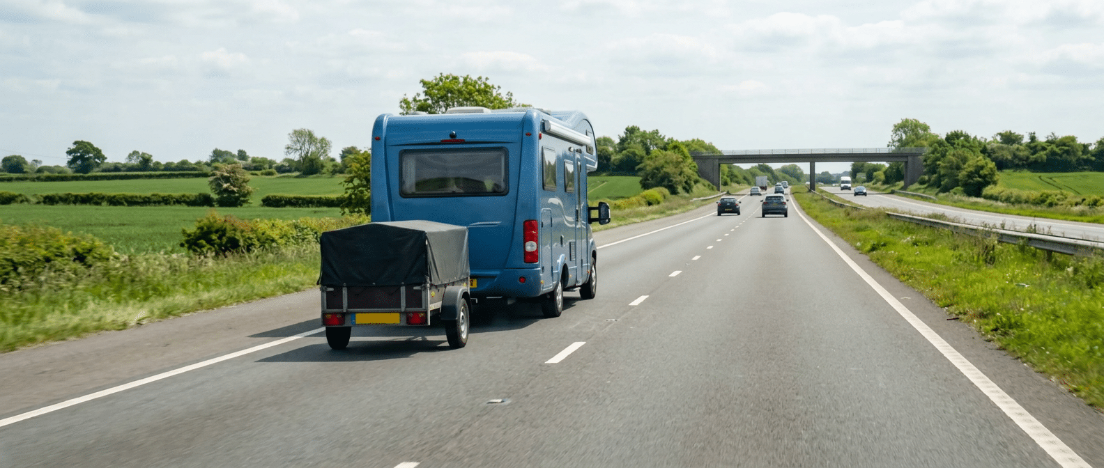 Caravana azul circulando por una carretera con un remolque o carga trasera acoplada